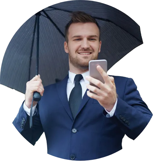 Ein lächelnder Mann im Anzug mit Regenschirm, der ein Smartphone hält